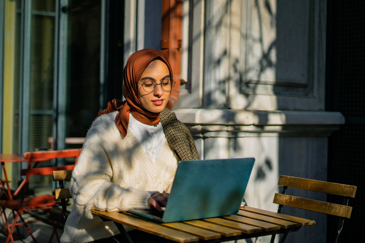 Femme assise à une table en plein air avec son ordinateur portable